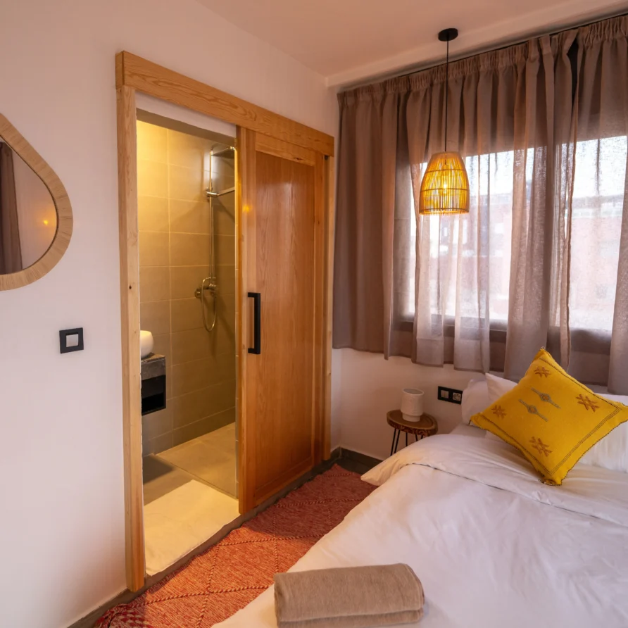 Double bed with pillows and sunlight in Magic Room, Imsouane surf camp
