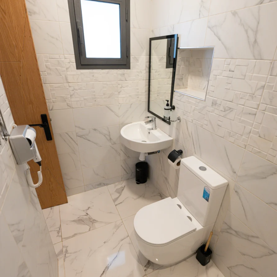 Sink, mirror, toilet and wall hairdryer in the room’s private bathroom.